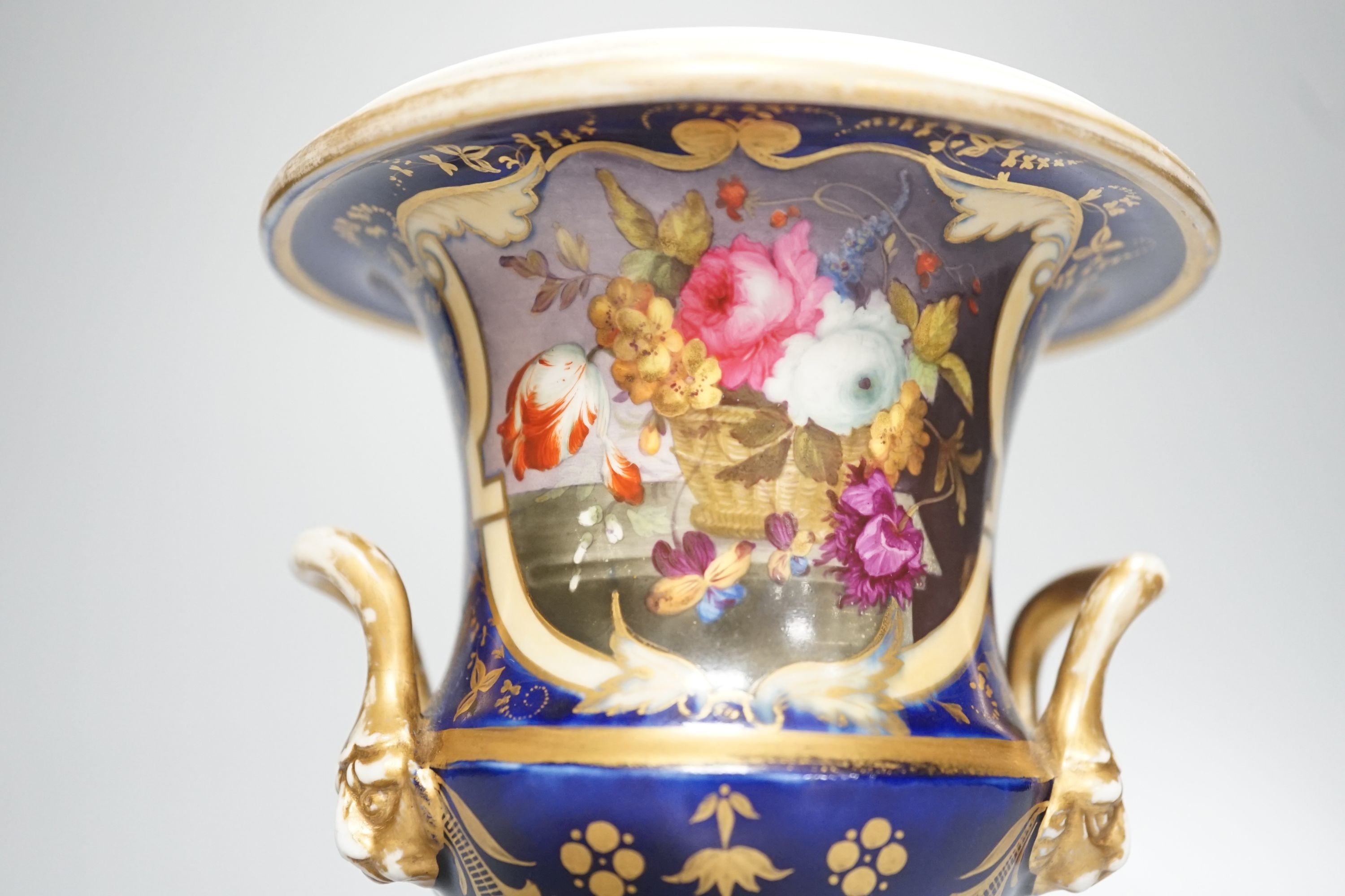 A Herculaneum two handled pedestal campana shaped vase, painted with basket of flowers, within a shaped cartouche on a cobalt blue and gilt ground, c.1815, height 14.5cm